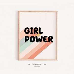 May include: A framed print with a colourful striped background and the text "GIRL POWER" in black bold letters. The print has a light wood frame.