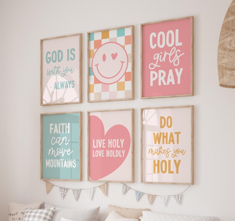 May include: A collection of six framed art prints with inspirational quotes and designs. The prints feature phrases like "God is with you always" and "Cool girls pray" in various colors, including pink, blue, and yellow. The artwork is displayed on a white wall.