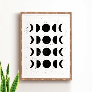 May include: Black and white print of a moon phases design in a wooden frame. The print features a repeating pattern of moons in different phases, from a crescent to a full moon.