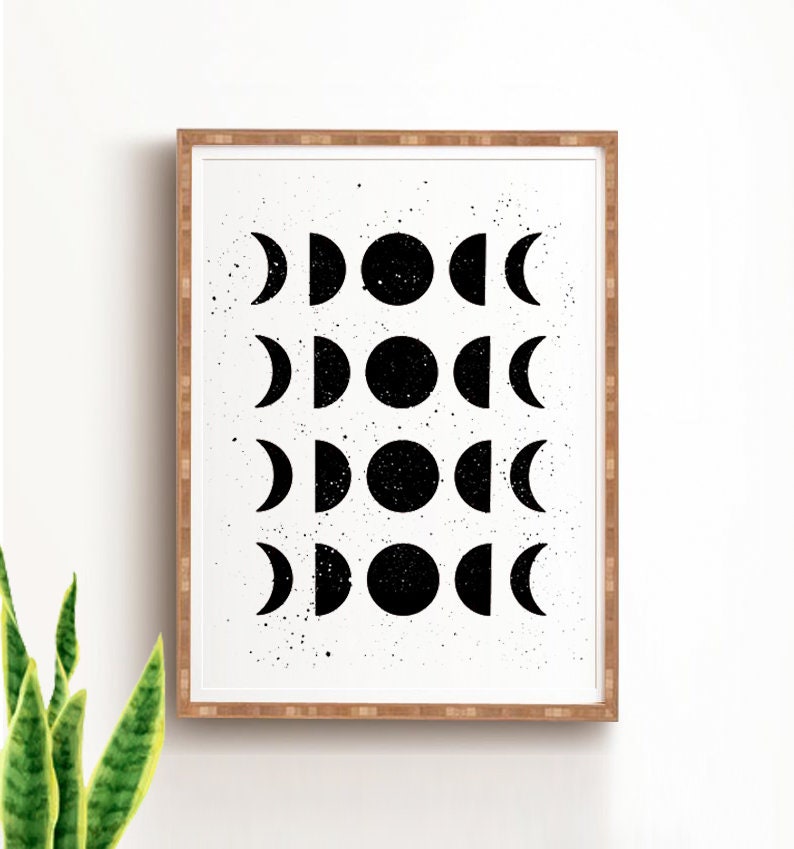 May include: Black and white print of a moon phases design in a wooden frame. The print features a repeating pattern of moons in different phases, from a crescent to a full moon.