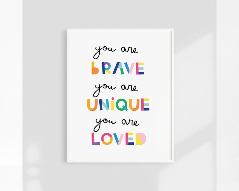 May include: A white framed print with the text "you are BRAVE you are UNIQUE you are LOVED" in colorful block letters.