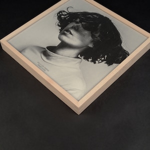 May include: A framed black and white photograph of a person with long hair. The photo is titled "NEVER LET ME DOWN AGAIN" and "DEBUT ALBUM".