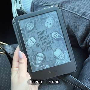 May include: A black e-reader device displaying a grayscale graphic of five horror movie characters surrounding the text DON'T TOUCH MY KINDLE, BITCH. The screen shows illustrations of a hockey mask, a ghost mask, a clown, a puppet, and a masked figure.