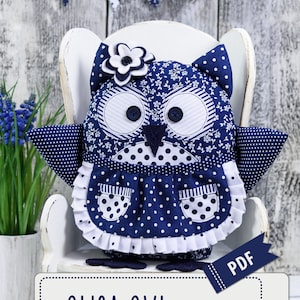 Puede incluir: Un patrón de costura PDF y un tutorial para hacer un juguete de peluche de búho azul y blanco con lunares. El patrón se llama "Olisa Owl" y es de "Blue Owl Land".