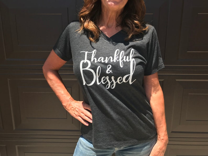 May include: A dark gray V-neck t-shirt with the text "Thankful & Blessed" in white lettering.