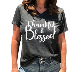 May include: A dark gray V-neck t-shirt with the text "Thankful & Blessed" in white lettering.