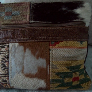 May include: A brown leather patchwork crossbody bag with a zipper closure. The bag is made of different materials, including leather, fur, and fabric. The bag has a long strap and a flap closure.