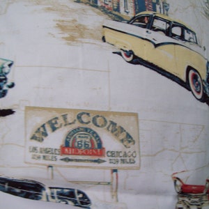 May include: A white fabric with a vintage Americana theme. The fabric features a welcome sign with Route 66, a classic car, and a map. The text on the sign reads "Welcome, Los Angeles 1539 Miles, Chicago 1539 Miles, Route 66, Midpoint!"