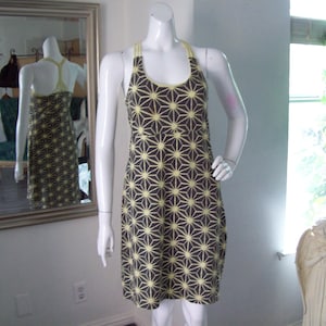 May include: A sleeveless dress with a geometric pattern in shades of brown and yellow. The dress has a scoop neck and a fitted bodice.