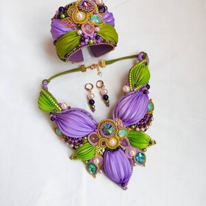 May include: A purple and green jewelry set with a necklace, bracelet, and earrings. The necklace and bracelet feature a floral design with intricate details and colorful beads. The earrings are simple and elegant.
