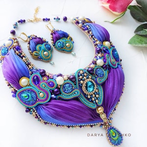 May include: A purple and blue silk ribbon necklace with gold accents and turquoise and pearl beads. Matching earrings are also included.