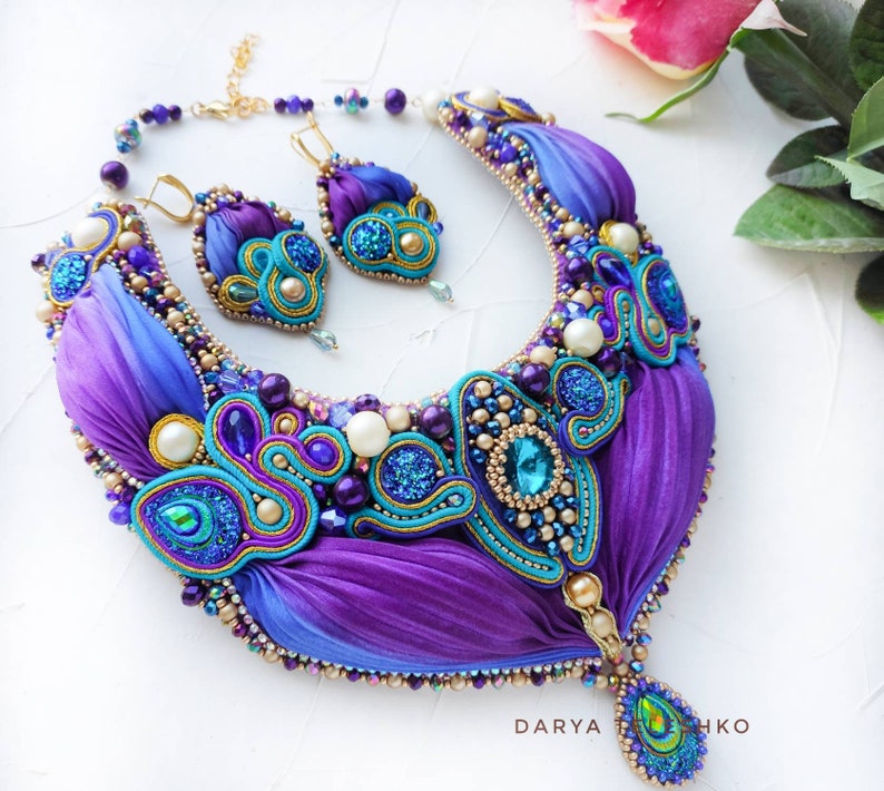 May include: A purple and blue silk ribbon necklace with gold accents and turquoise and pearl beads. Matching earrings are also included.