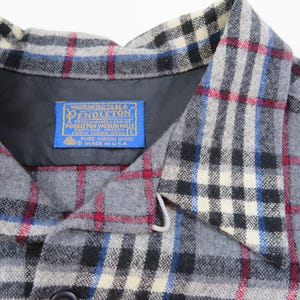 May include: A gray plaid shirt with a collar and a blue Pendleton label sewn into the inner neckline. The label reads Warranted to be a Pendleton, Pendleton Woolen Mills, Portland, Oregon, 100% Virgin Wool, Size L, Pure Virgin Wool, Made in U.S.A.