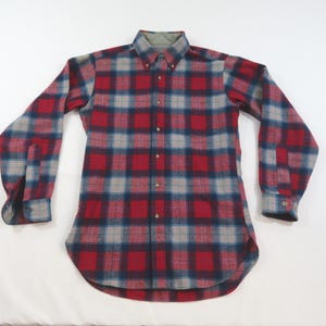 May include: A long-sleeve button-down shirt featuring a plaid pattern in shades of red, navy blue, and light gray. The shirt has a pointed collar, a front button placket, and buttoned cuffs on the sleeves, showcasing a classic woven textile design.