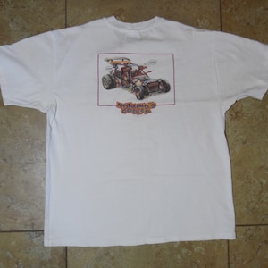 May include: White t-shirt with a cartoon illustration of a dune buggy with the text "Nothing's Cooler" printed on the back.