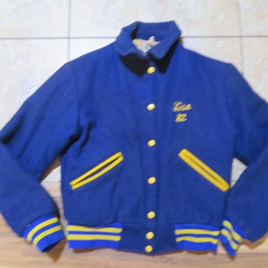 May include: A blue varsity jacket with yellow stripes on the sleeves and pockets. The jacket has a gold button closure and the name "Lisa 82" embroidered on the chest.