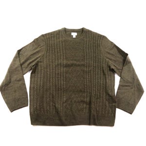 May include: An olive green long-sleeve sweater featuring a crew neckline and a textured knit pattern. The front panel displays a central diamond lattice design flanked by vertical cable knit columns, with plain knit sleeves and a ribbed hem.