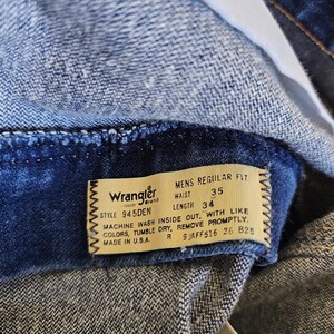 May include: Close-up of a pair of blue denim jeans. The jeans have a label that reads "Wrangler" and includes the waist size 35 and length 34. The label also provides washing instructions. Made in the U.S.A.