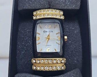 Orologio da polso da donna Gruen con cinturino rigido nero e dettagli in oro, quadrante bianco, al quarzo