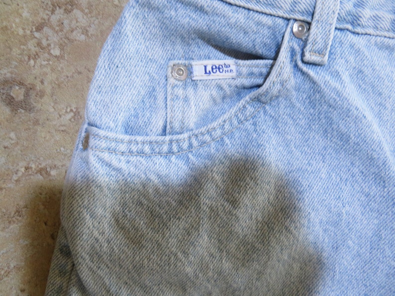 May include: Light blue denim jeans with a faded appearance and a Lee brand label on the front pocket.
