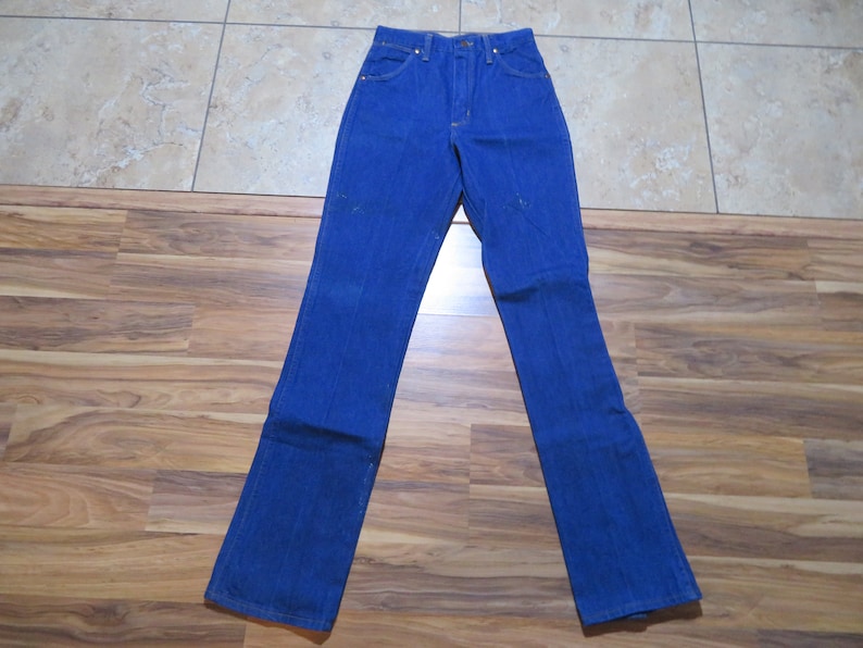 May include: A pair of blue denim jeans with a straight leg fit. The jeans have a classic five-pocket style and a button fly.