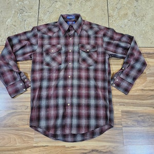 May include: A long-sleeved, button-down shirt with a plaid pattern in shades of burgundy, gray, and black. The shirt has two chest pockets and a classic collar. The cuffs are buttoned. This shirt is suitable for casual wear.