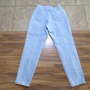 May include: Light blue denim jeans with a high waist and a straight leg. The jeans have a classic five-pocket style.