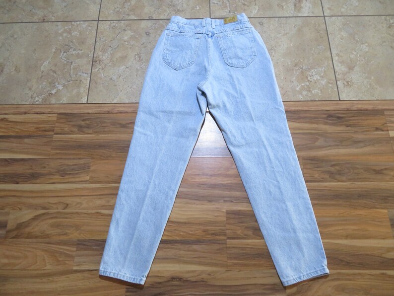 May include: Light blue denim jeans with a high waist and a straight leg. The jeans have a classic five-pocket style.