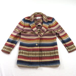 May include: A long-sleeve blazer featuring a horizontal striped pattern in shades of red, blue, tan, and brown. The garment has a notched lapel, a single front button closure, and two large rectangular patch pockets on the lower front section.