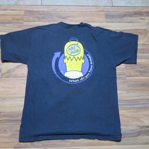 Puede incluir: Camiseta azul marino con un personaje de dibujos animados amarillo con el texto "Intel Inside" dentro de su cabeza. El diseño está rodeado por un círculo azul y una flecha. También está presente el texto "What do you have inside?"