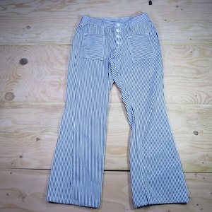 May include: Blue and white striped pants with a button fly and two patch pockets. The pants have a wide leg.