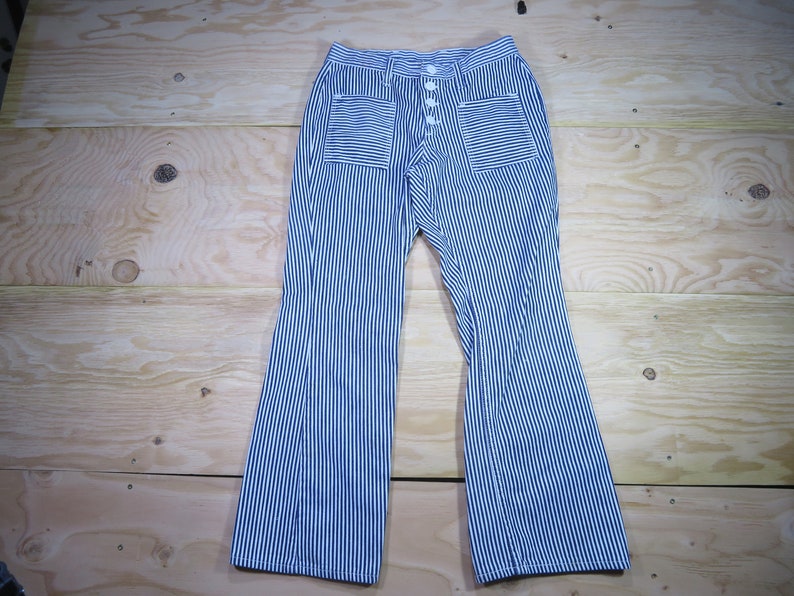 May include: Blue and white striped pants with a button fly and two patch pockets. The pants have a wide leg.