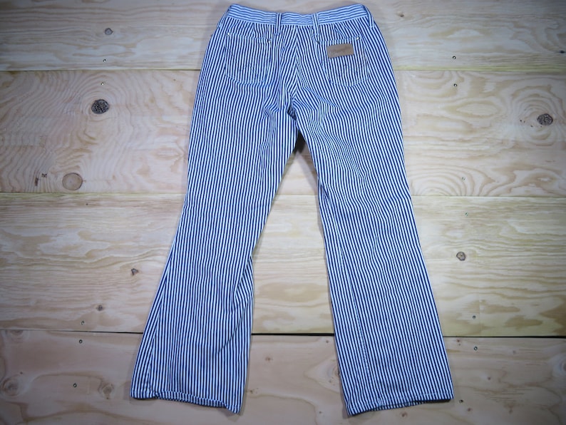 May include: Blue and white striped pants with a wide leg. The pants have a brown leather patch on the back right pocket.