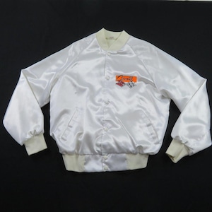 May include: A white satin bomber jacket featuring a ribbed collar, cuffs, and hem. The front displays an embroidered logo patch with the text Corvette in orange script above two crossed checkered racing flags on the left chest area.