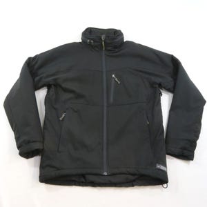 Può includere: Una giacca nera a maniche lunghe con collo alto, chiusura frontale con zip integrale e due tasche laterali con zip. È presente una tasca verticale con zip sul petto sinistro e un piccolo logo applicato è visibile sul capo.