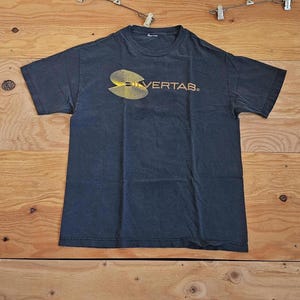 May include: A dark grey t-shirt featuring a yellow and black graphic and the word "SILVERTAB". The short-sleeved shirt has a crew neck and is made of a soft material.