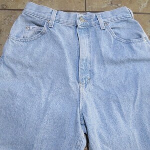 May include: Light blue denim jeans with a high waist and a classic five-pocket style. The jeans have a faded look and a relaxed fit.