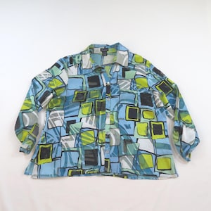 May include: A long-sleeve button-down shirt featuring a vibrant geometric pattern of overlapping squares in shades of light blue, lime green, black, and white. The garment has a classic collar, a full-length front button placket, and long sleeves.
