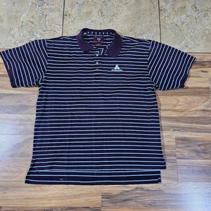 May include: A short-sleeved polo shirt with horizontal stripes in navy blue and light blue. The shirt has a dark purple collar and a small white logo on the chest. The shirt is made of a soft, breathable fabric.