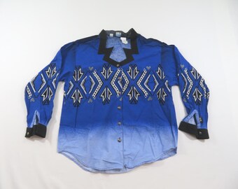 May include: A long-sleeve button-down shirt featuring a vibrant blue ombre effect that fades to a lighter shade at the hem. The shirt displays a prominent black collar and black cuffs, accented by a geometric white, black, and grey pattern across the chest.