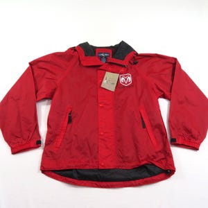May include: A bright red windbreaker jacket featuring a black inner collar and hem lining. The jacket has a front snap button closure, two zippered side pockets, and a white Dodge Ram logo on the chest. A cardboard product tag is attached to the front.