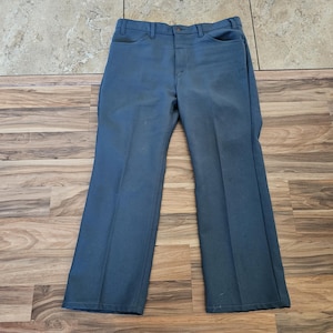 May include: A pair of blue denim pants with a classic five-pocket design. The pants have a straight leg cut and a button and zipper closure. The pants are made of a durable denim material.