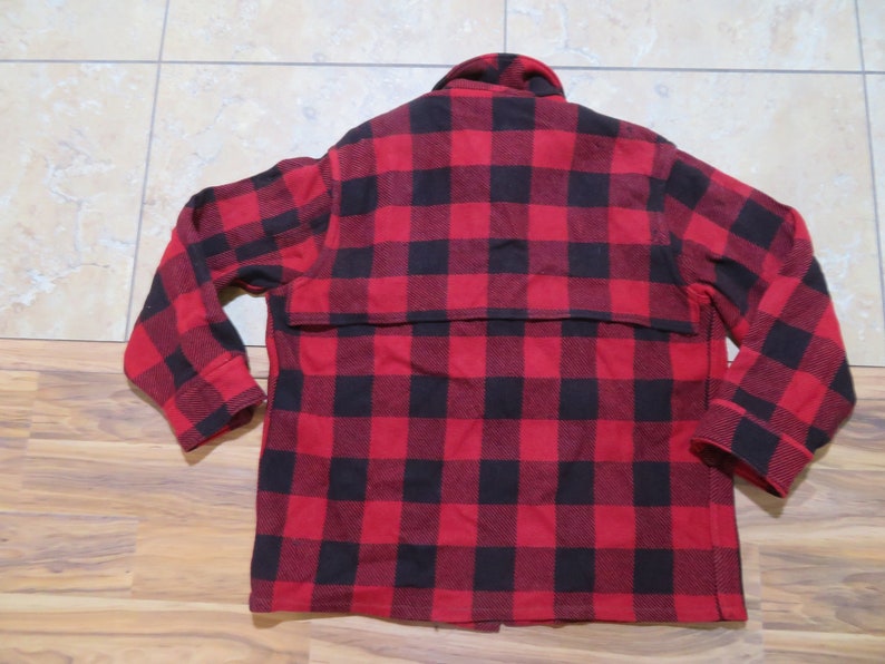 May include: A long-sleeve button-up shirt featuring a bold red and black buffalo plaid pattern. The garment includes a classic collar, a horizontal back yoke overlay, and cuffs at the end of each sleeve, showcasing a consistent checkered design.