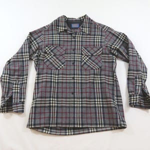 Puede incluir: Una camisa de manga larga con botones y un patrón de cuadros en gris, negro, blanco y granate. La camisa incluye un cuello puntiagudo, dos bolsillos en el pecho con solapas abotonadas y puños con botones. La etiqueta Pendleton es visible en el cuello.