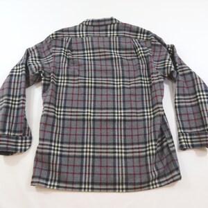 May include: A long-sleeve button-down shirt featuring a gray, black, white, and maroon plaid pattern. The garment has a standard collar, buttoned cuffs, and a straight hemline, displayed from the back view against a plain white background.