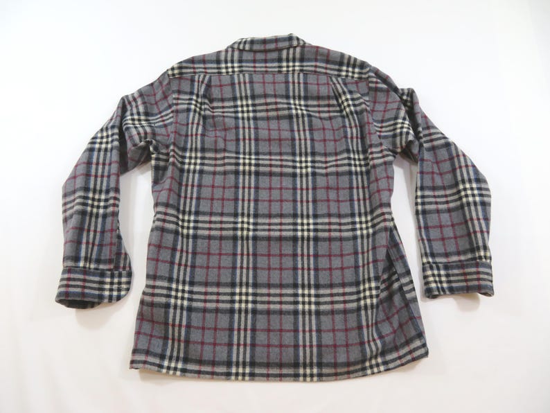 May include: A long-sleeve button-down shirt featuring a gray, black, white, and maroon plaid pattern. The garment has a standard collar, buttoned cuffs, and a straight hemline, displayed from the back view against a plain white background.