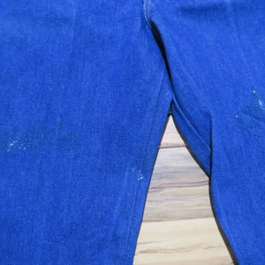 May include: A pair of blue denim jeans with visible wear and tear on the fabric.