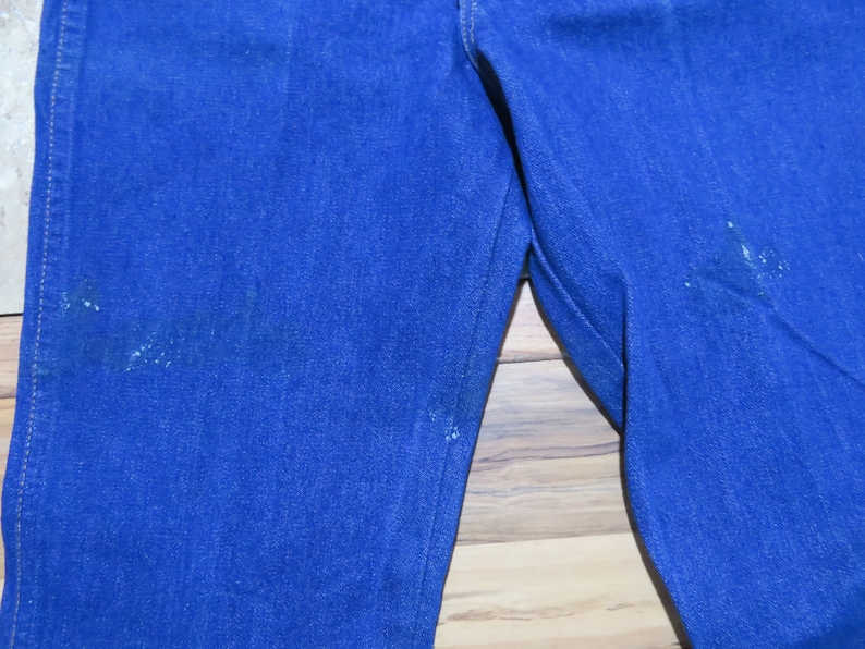 May include: A pair of blue denim jeans with visible wear and tear on the fabric.
