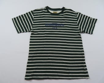 Könnte beinhalten: Grün-weiß gestreiftes T-Shirt mit kurzen Ärmeln. Das Shirt hat einen Rundhalsausschnitt und ein kleines Logo auf dem linken oberen Ärmel. Der Text "OUTDOOR LIVING INC." ist in Marineblau auf die Brust gedruckt.