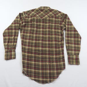 May include: A long-sleeve button-down shirt featuring a plaid pattern in shades of tan, brown, black, and dark red. The shirt has a pointed western-style back yoke, a standard collar, and long sleeves with buttoned cuffs, shown from the back view.